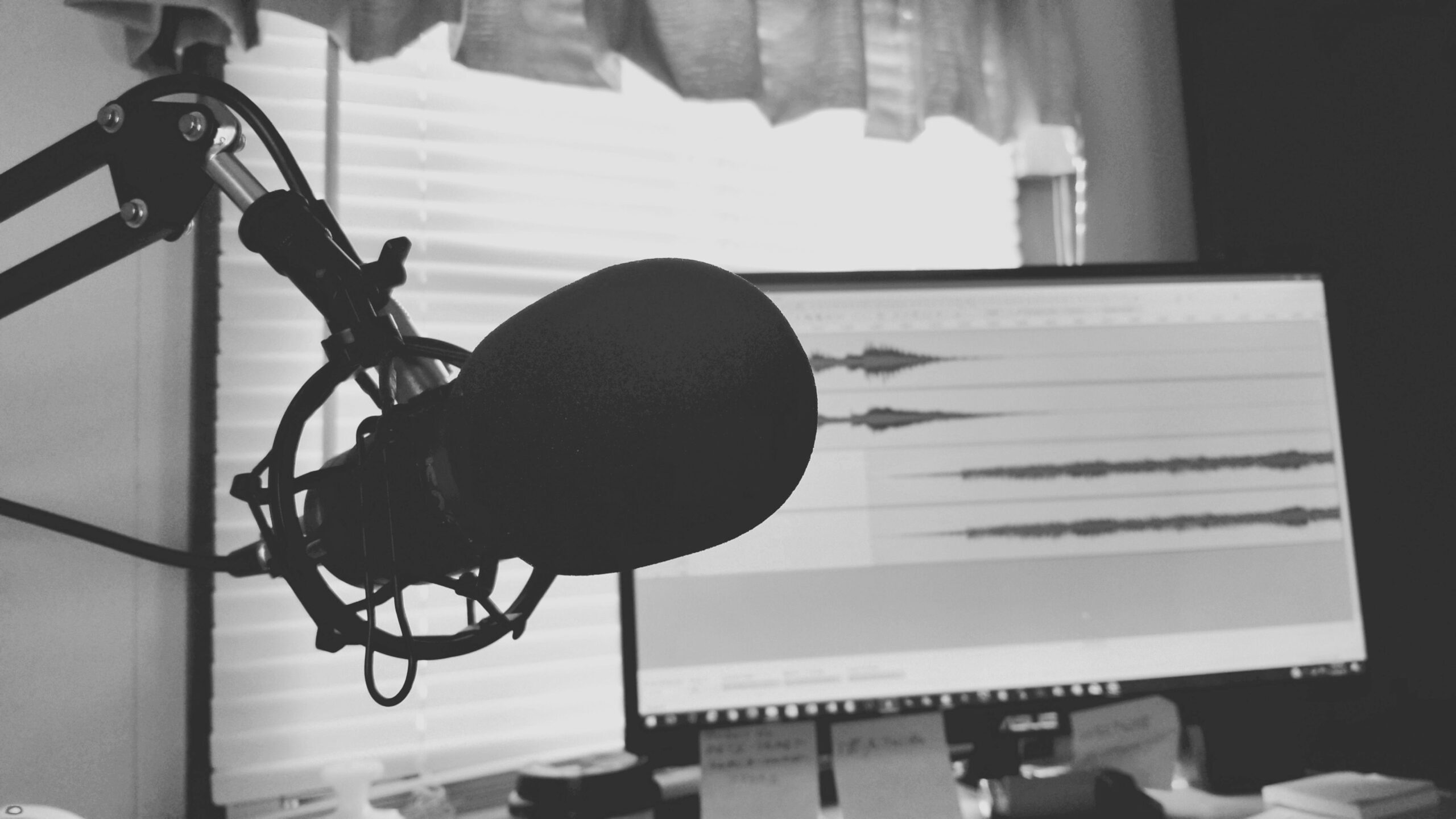 Black and white photo of a podcast microphone with an audio waveform on screen, representing an ElevenLabs voice model review