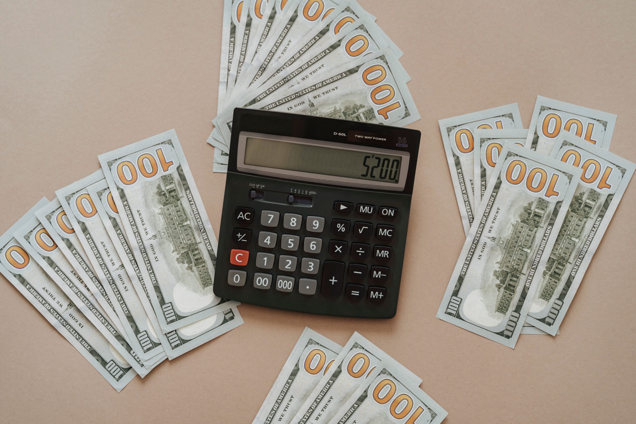 A calculator sits beside stacked dollar bills, representing calculating an ElevenLabs subscription cost