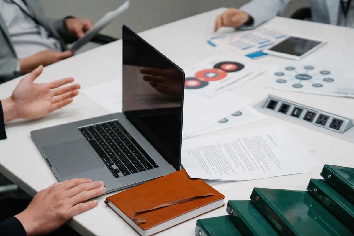 A person checking figures on a laptop against a printed report