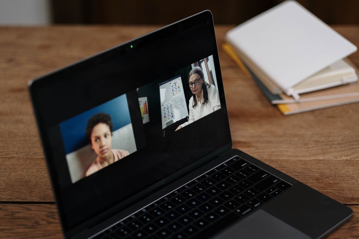 A laptop showing a video call with a presenter and slides side by side
