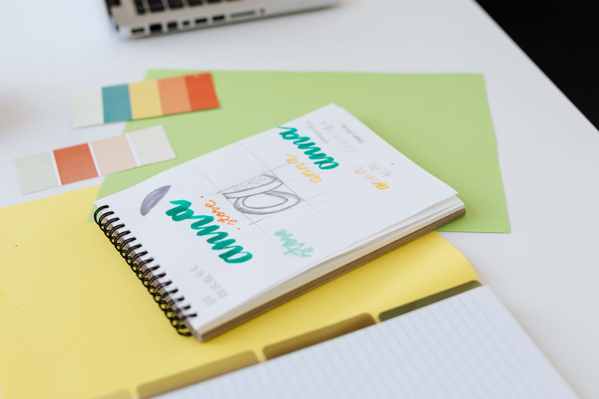 A brand style guide with colors, fonts, and logo on a designers desk