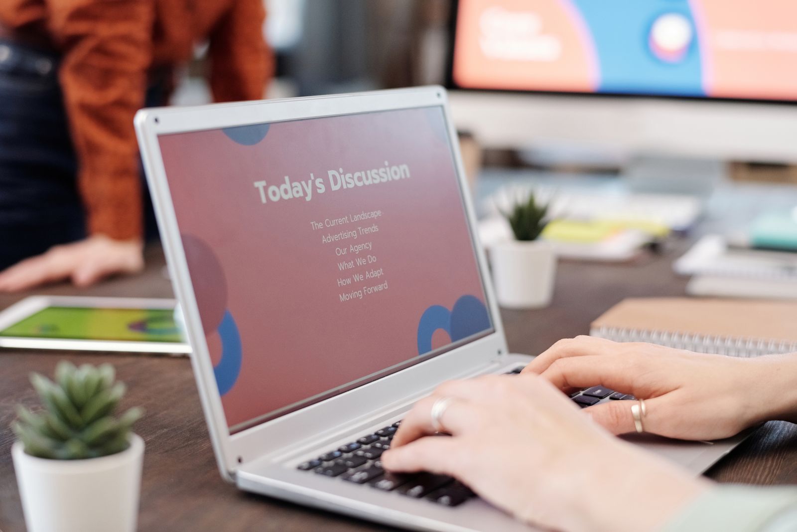 A laptop on a desk showing presentation design software with slide layouts