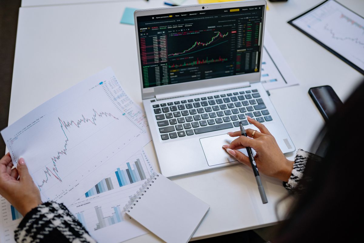 A laptop showing data charts and a spreadsheet on a desk
