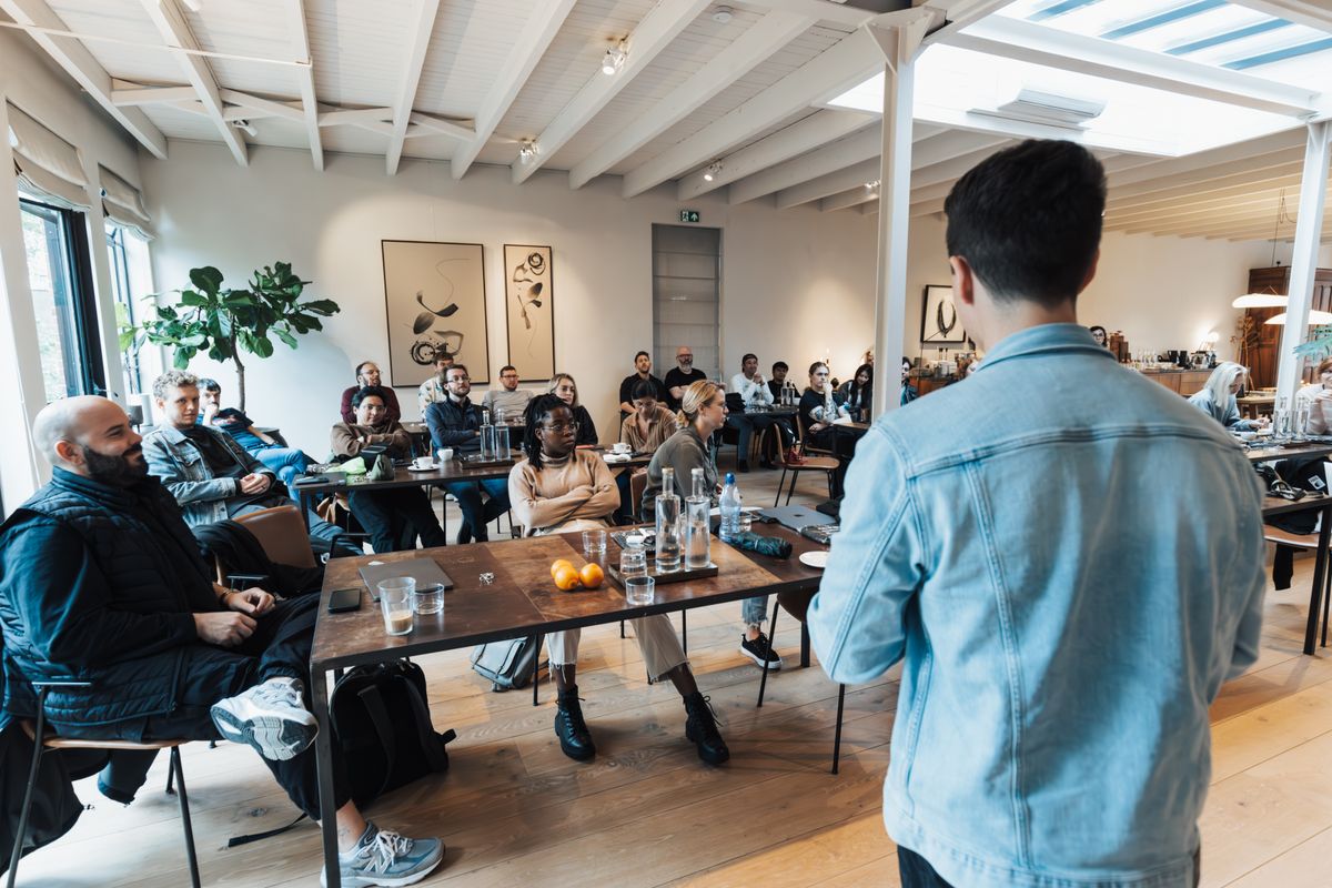 A sales rep presenting to an engaged, seated audience in a bright modern room