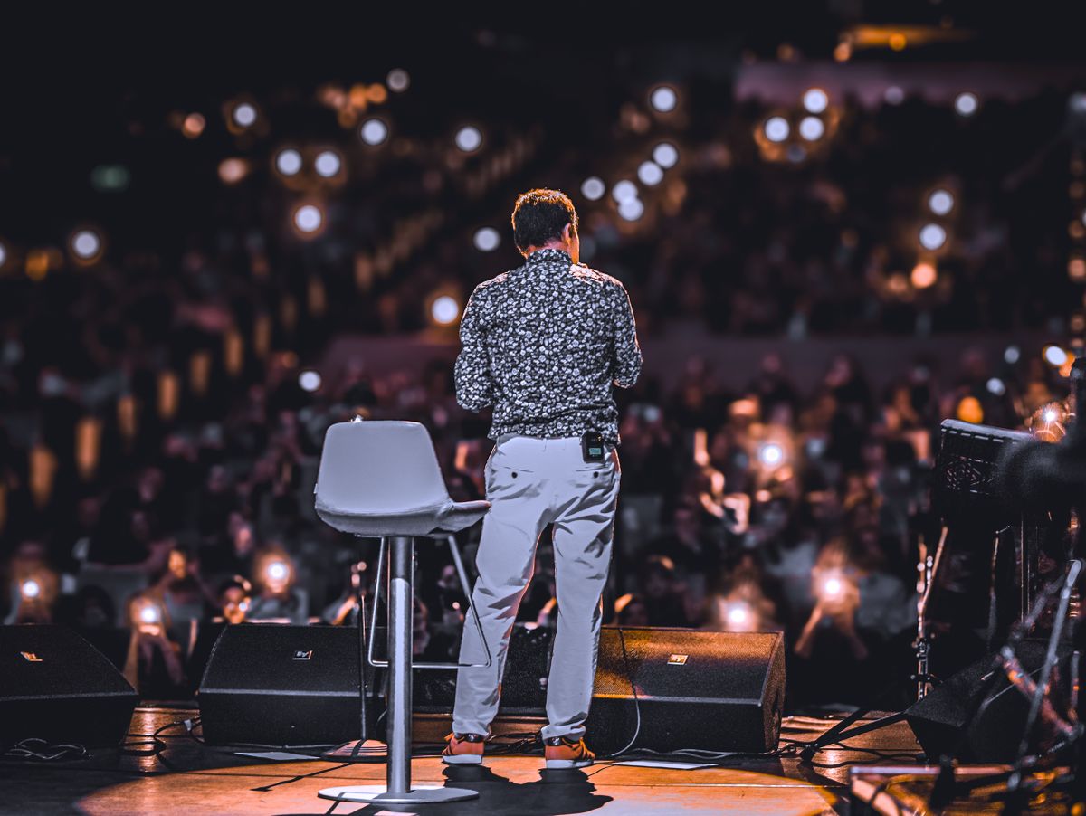 A founder presenting on a demo-day stage to an audience