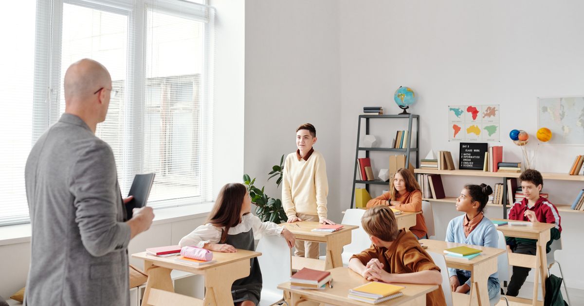 A teacher instructing a diverse group of students in a modern classroom