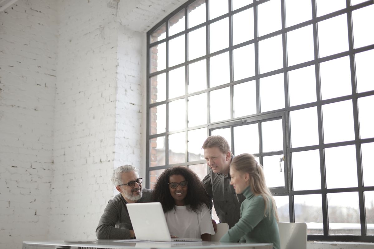 A team collaborating on a presentation together around laptops in a meeting room