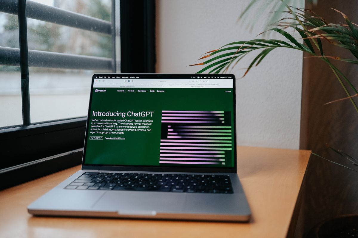 A laptop showing an AI chat open on a desk by a window in a home office