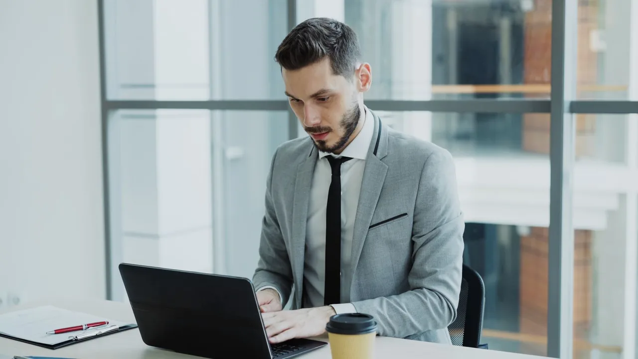 A small-business owner working on a laptop in a modern office