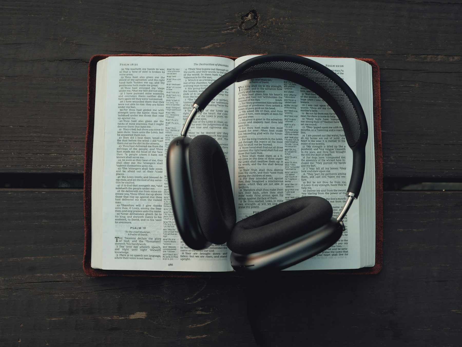 Wireless headphones resting on an open book page, representing text-to-speech and audio reading tools