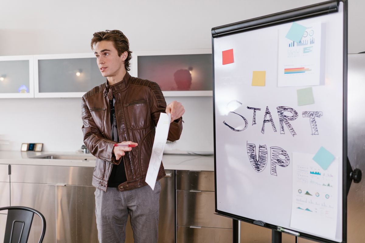 A founder presenting startup strategy on a flip chart to a small audience