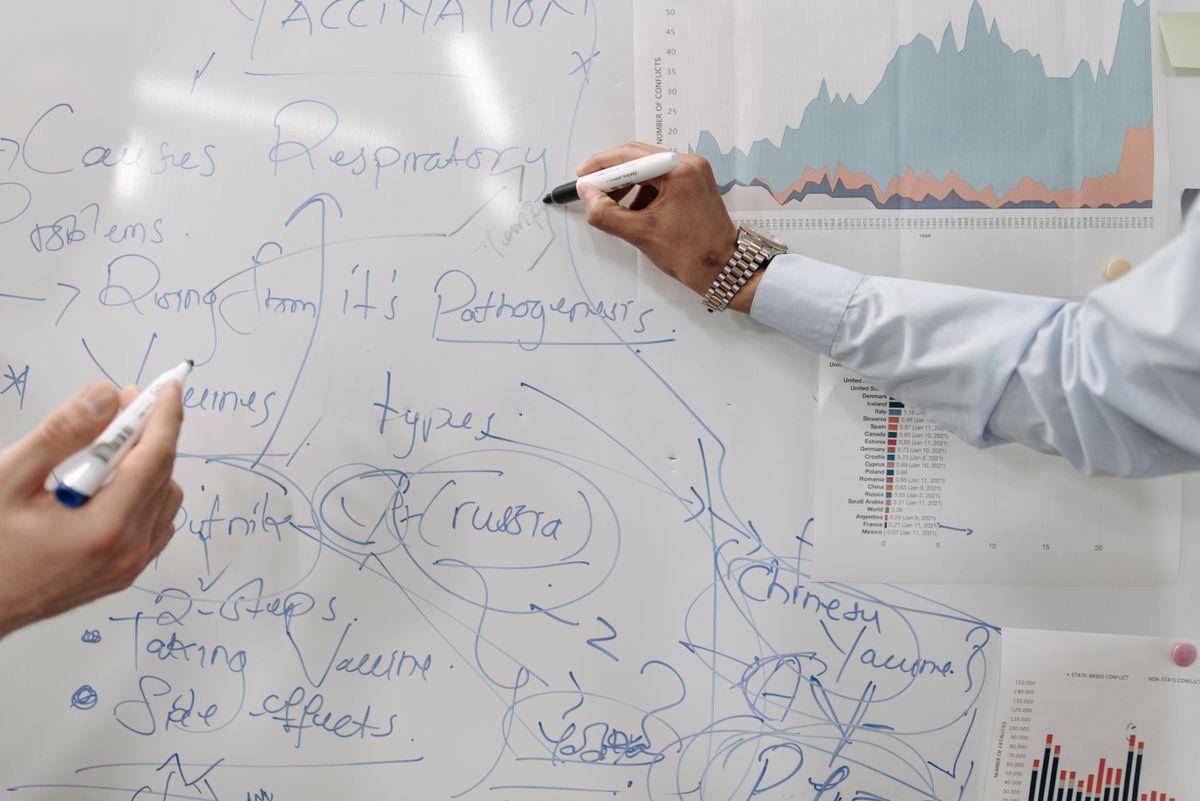 A person planning the structure of a presentation with notes and a laptop