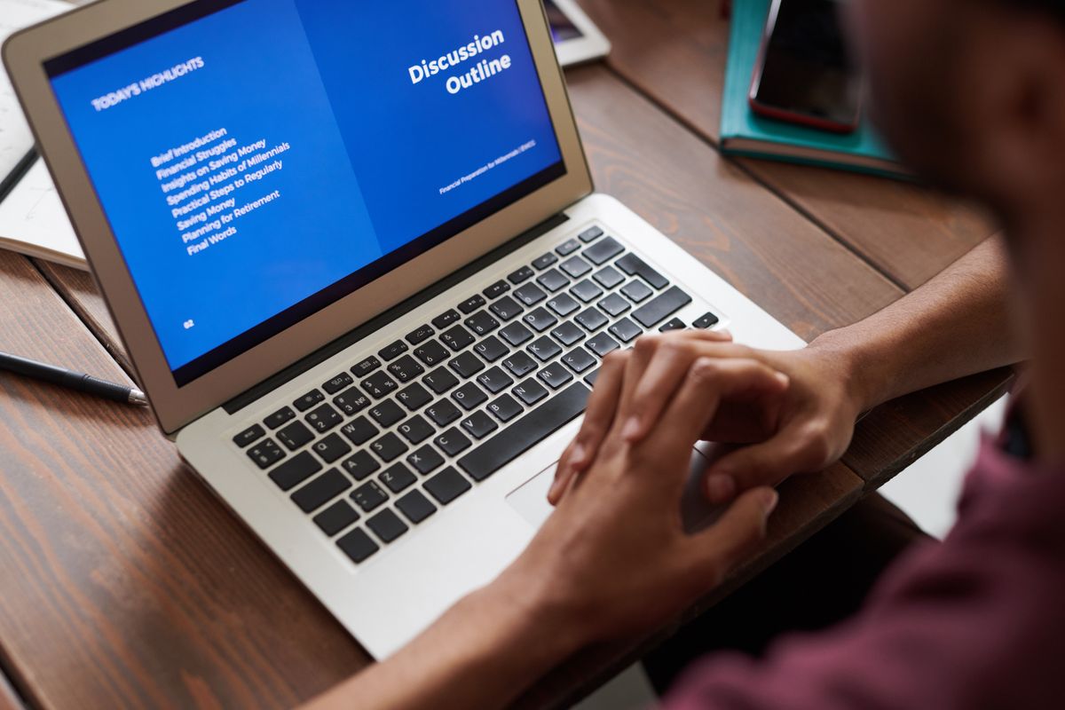 A person building a presentation on a laptop at a bright desk