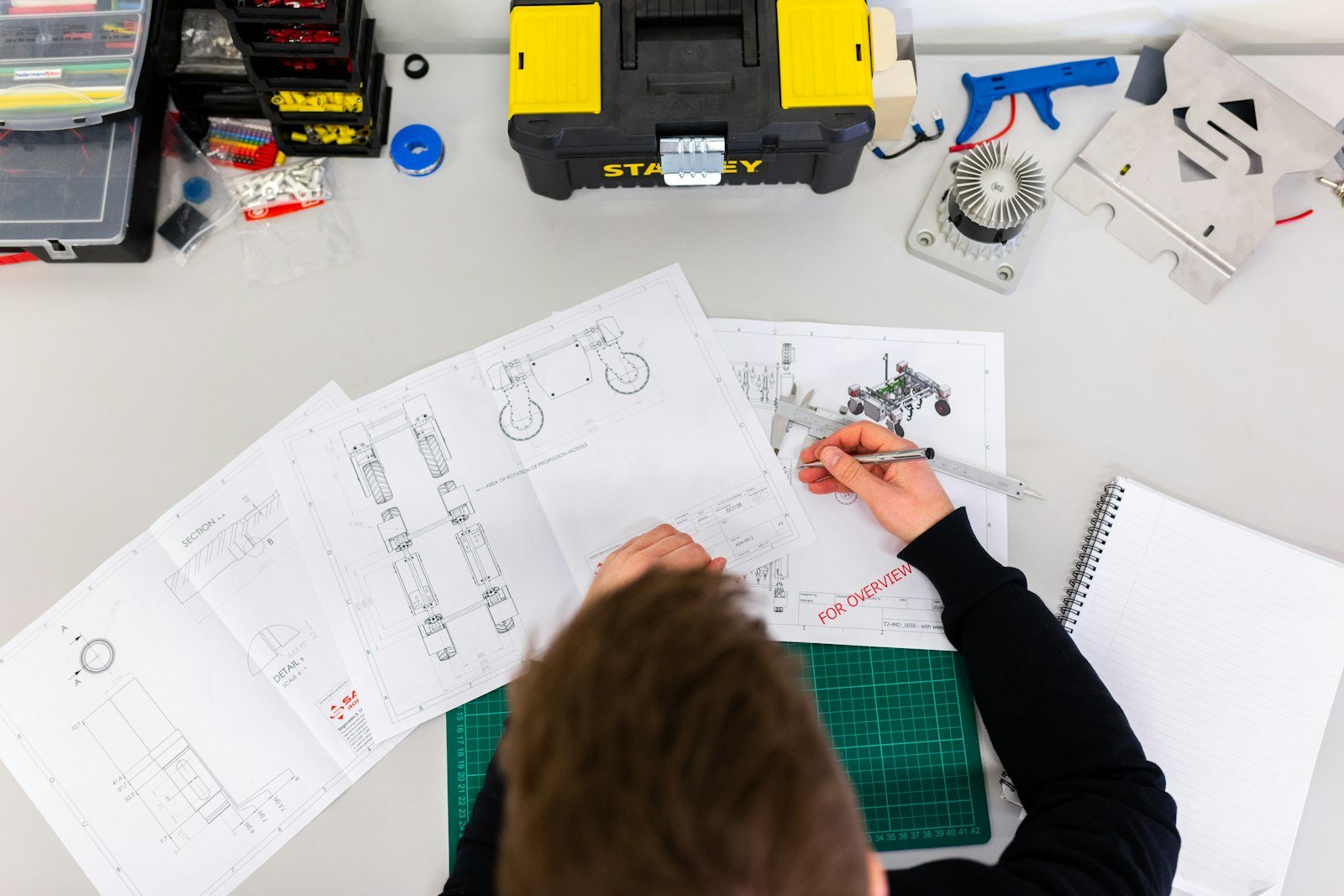 Engineer using a caliper to check measurements on a technical drawing