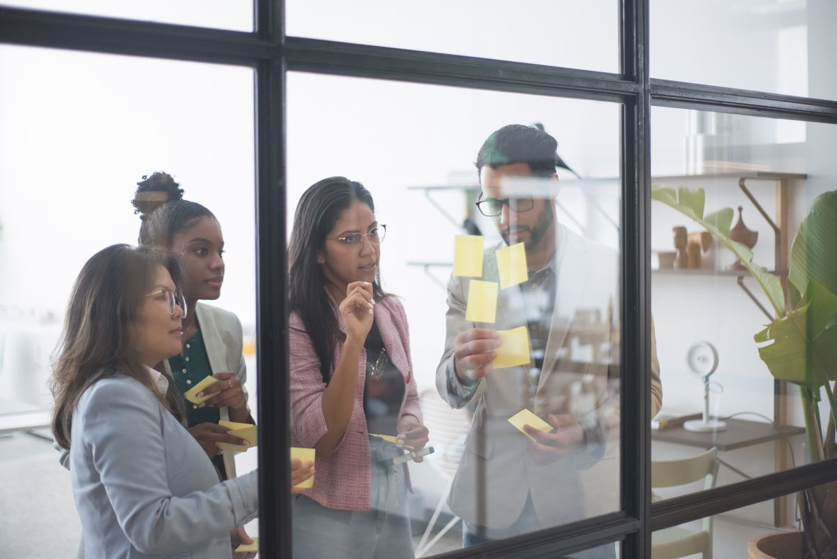 A group of business people in a meeting, the source of the notes behind a recap deck