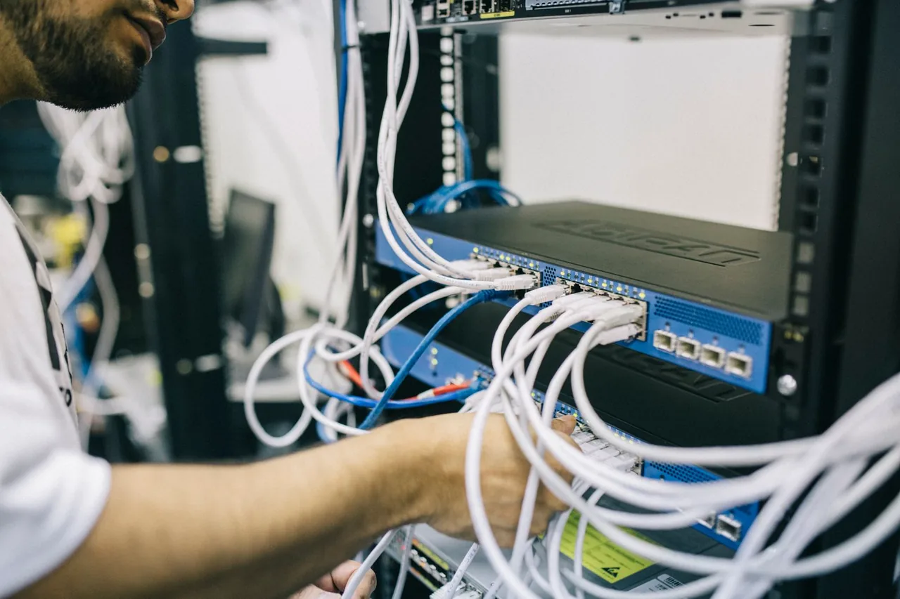 A network engineer connecting Ethernet cables to a rack-mounted network switch