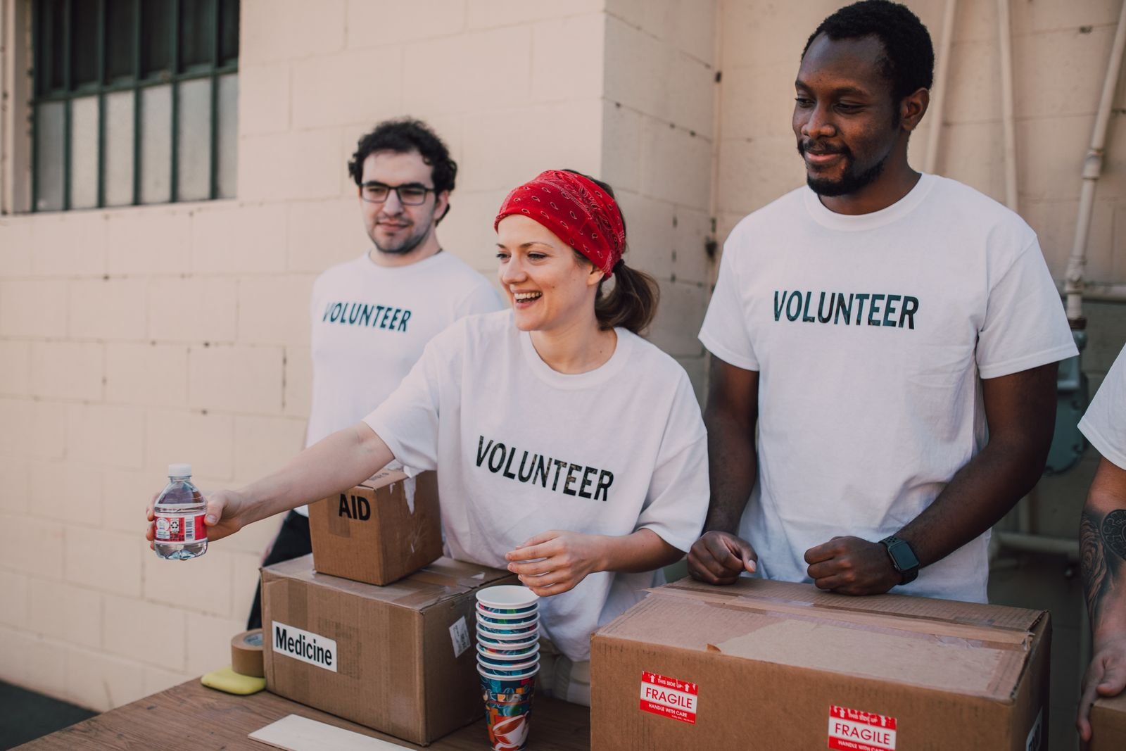 Three volunteers in Volunteer shirts sorting aid boxes