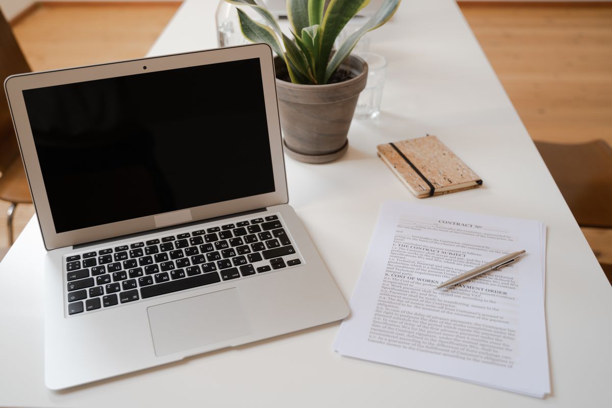 A laptop beside printed documents on a desk, ready for converting a PDF into slides