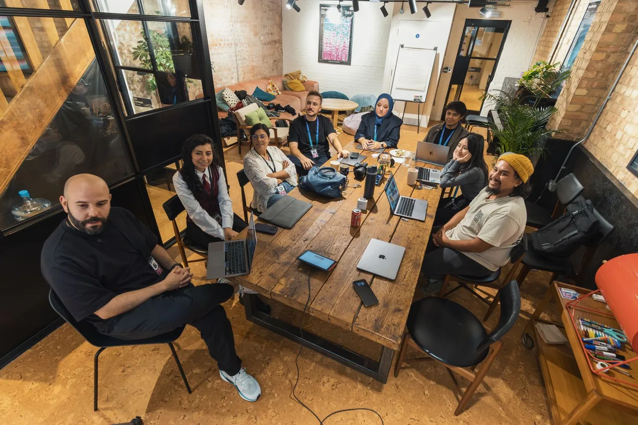 A small startup team collaborating around laptops in a modern workspace