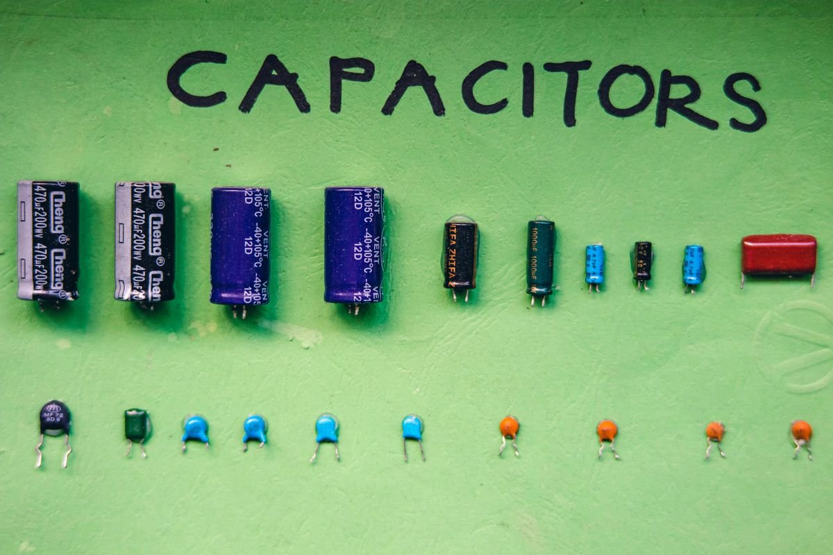 Electrolytic and ceramic capacitors sorted by value on a labeled board for parametric selection