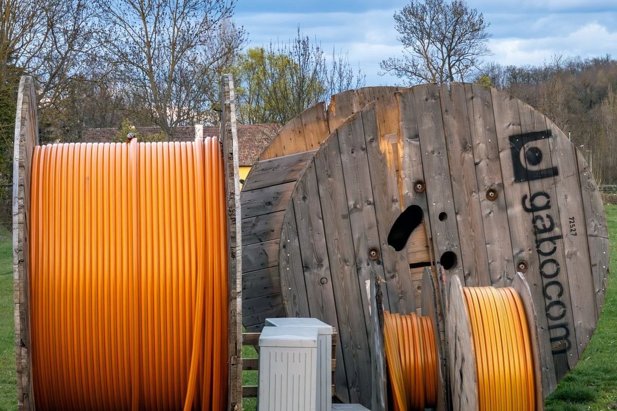 Wooden reels of orange power cable stored in an outdoor yard