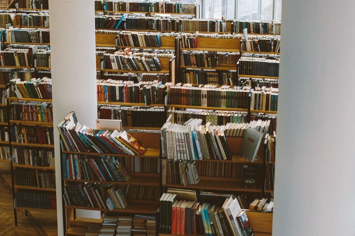 Rows of wooden bookshelves in a large library, representing the literature AI research tools search