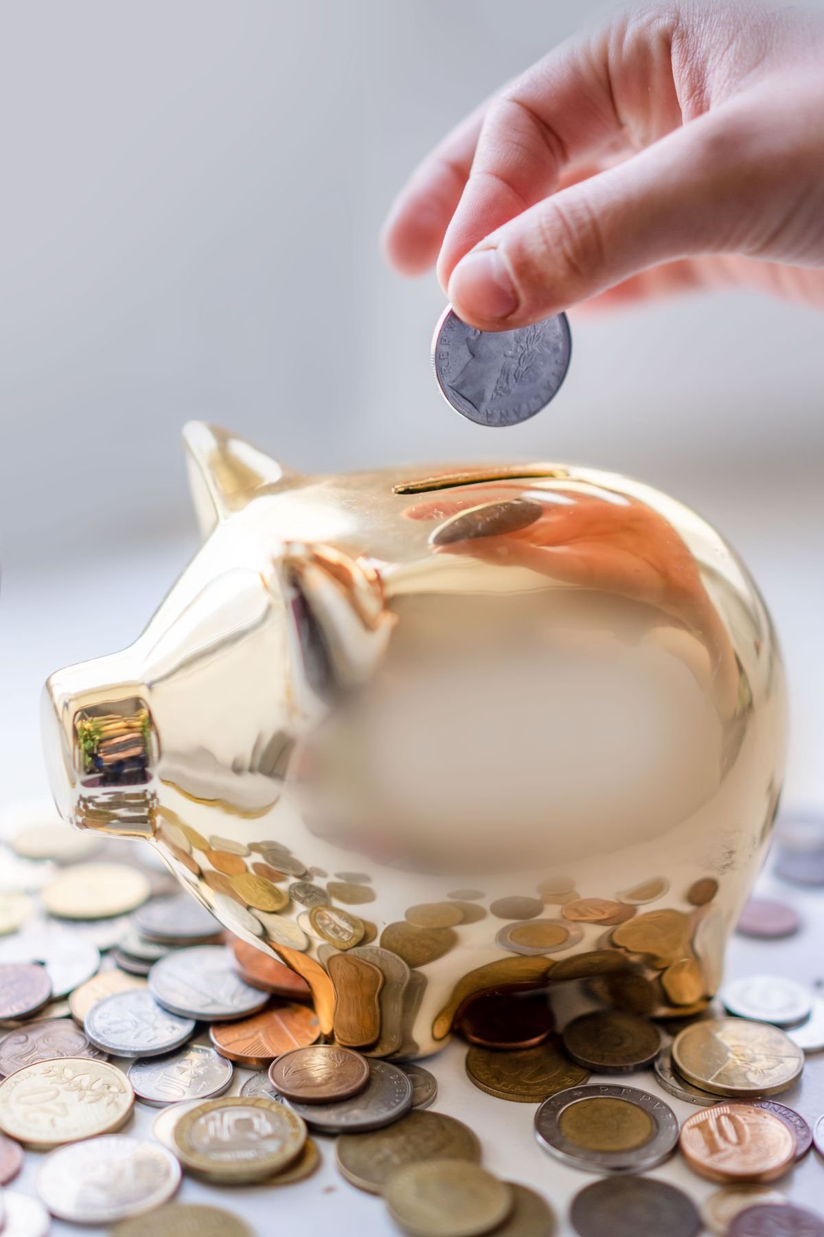 A hand dropping a coin into a golden piggy bank, representing budgeting for AI research tool subscriptions