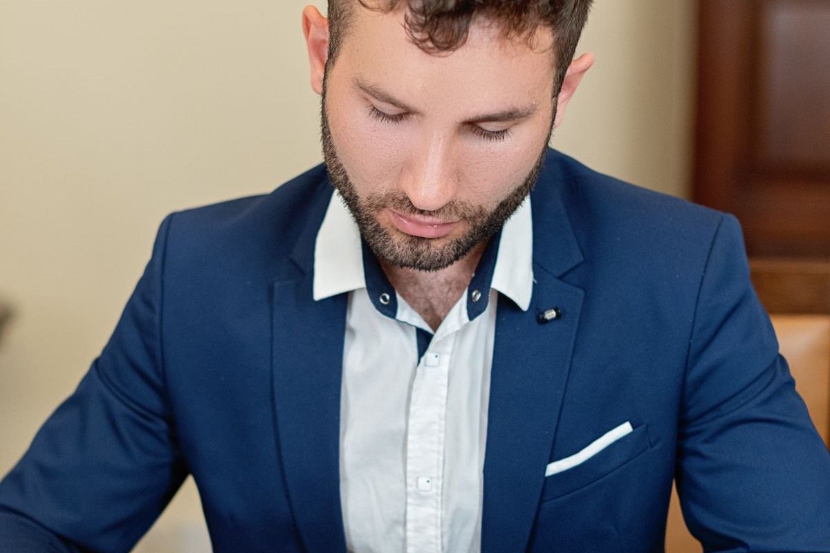 A professional in a suit reviewing and signing a legal document at a desk beside a law reference book