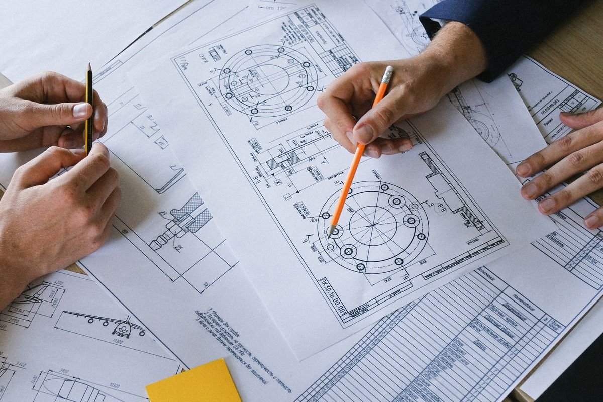 A small engineering team reviewing project drawings together around an office table