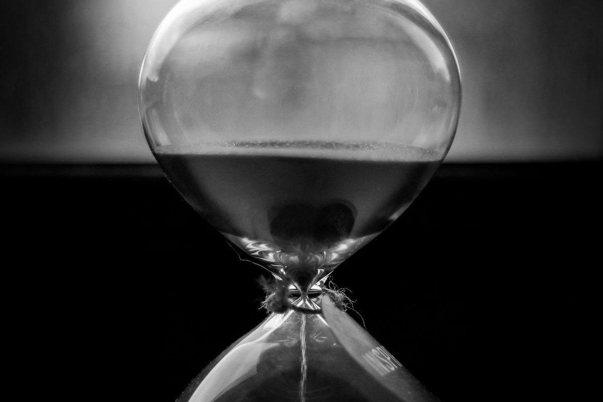 A black and white hourglass with sand running through it, representing rolling-window usage limits on AI tools