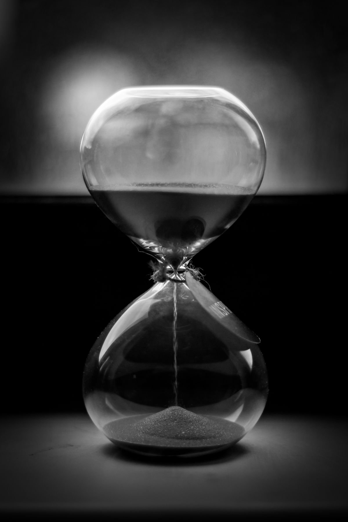A black and white hourglass with sand running through it, representing rolling-window usage limits on AI tools