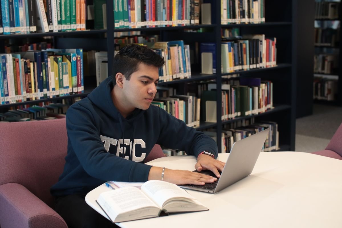 Researcher using a laptop for AI-assisted literature review in a library