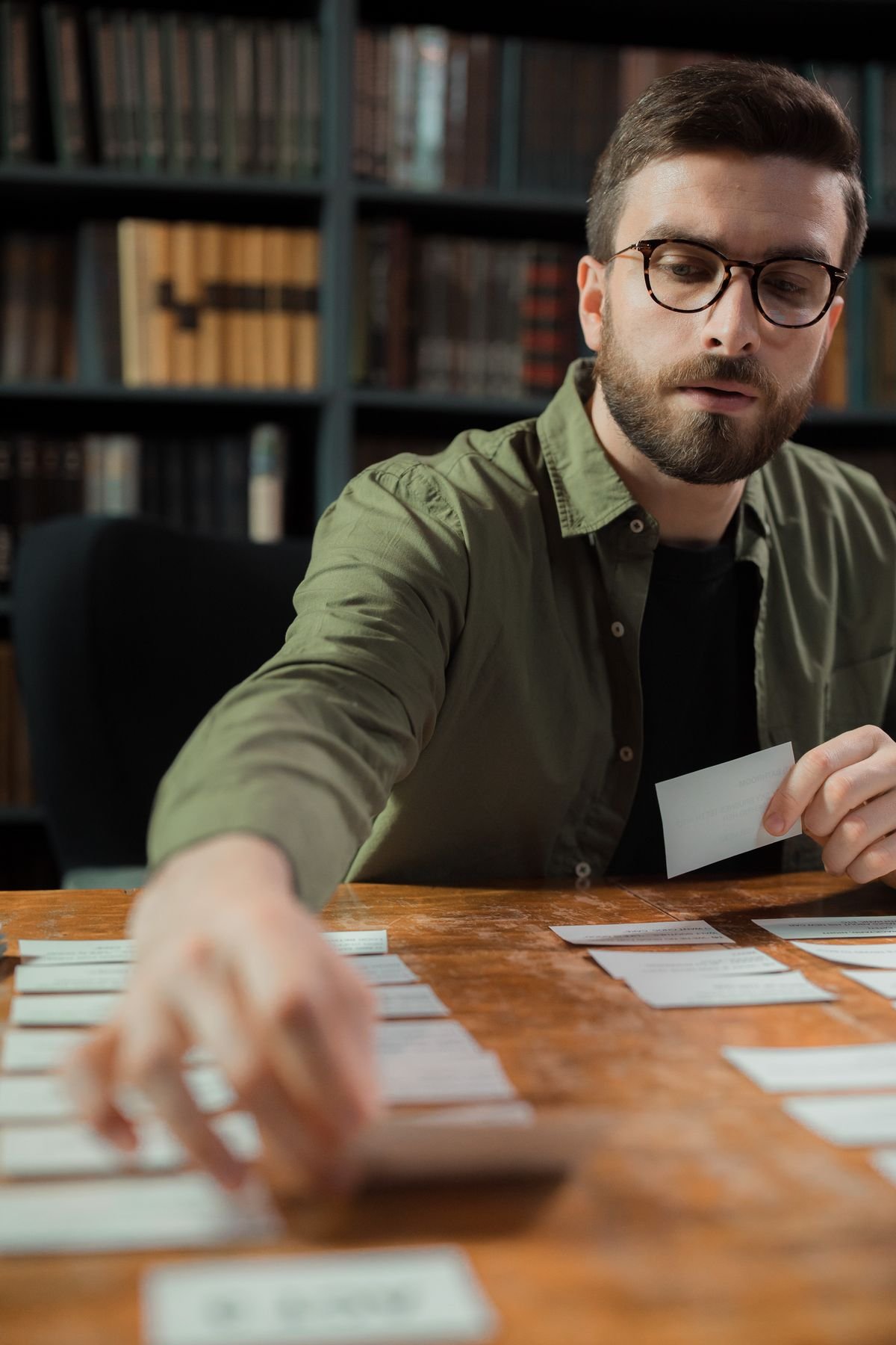 Engineering student sorting flashcards on a library table for active recall
