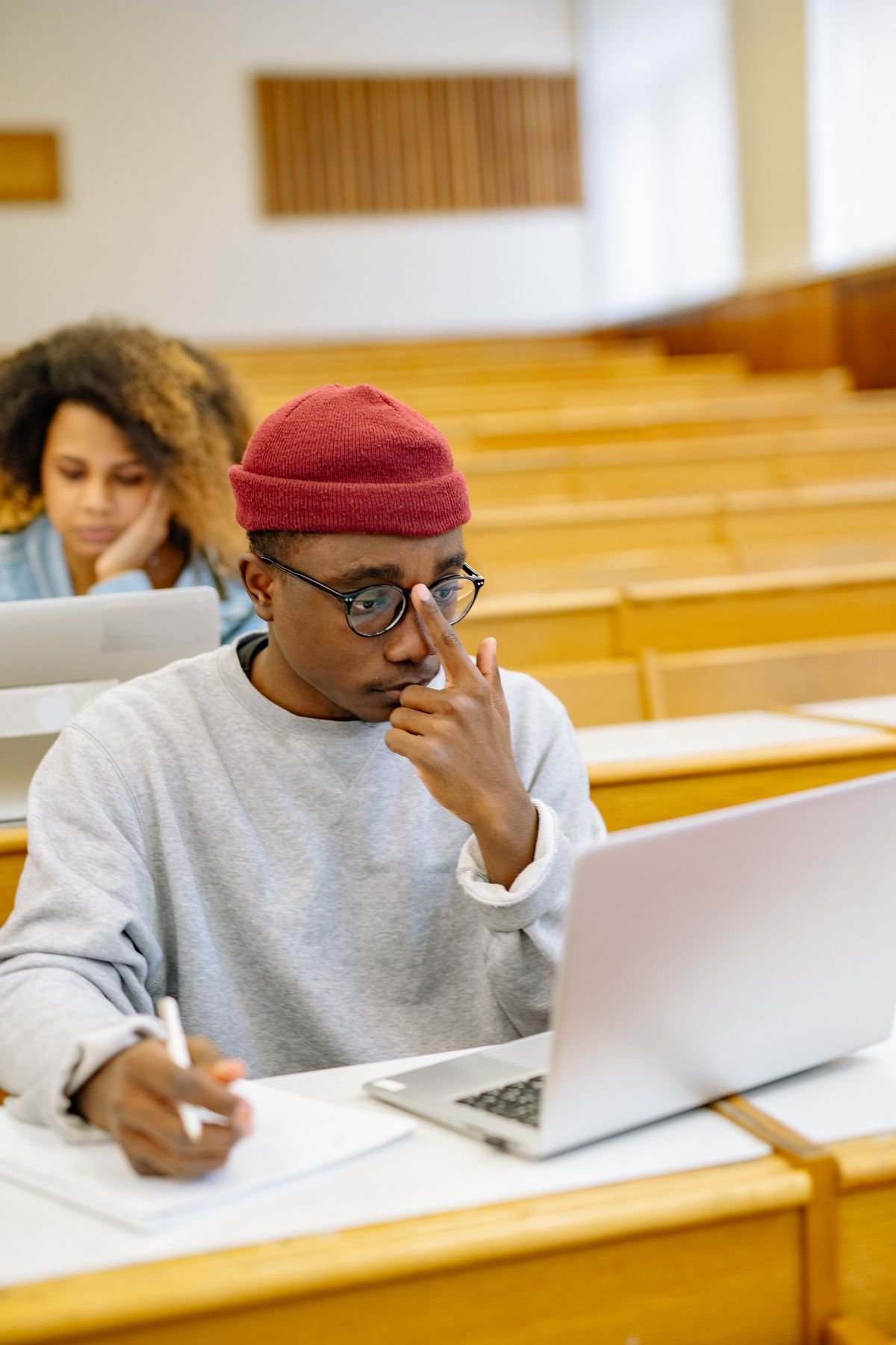 Two students collaborating over a laptop and notebooks in a study space