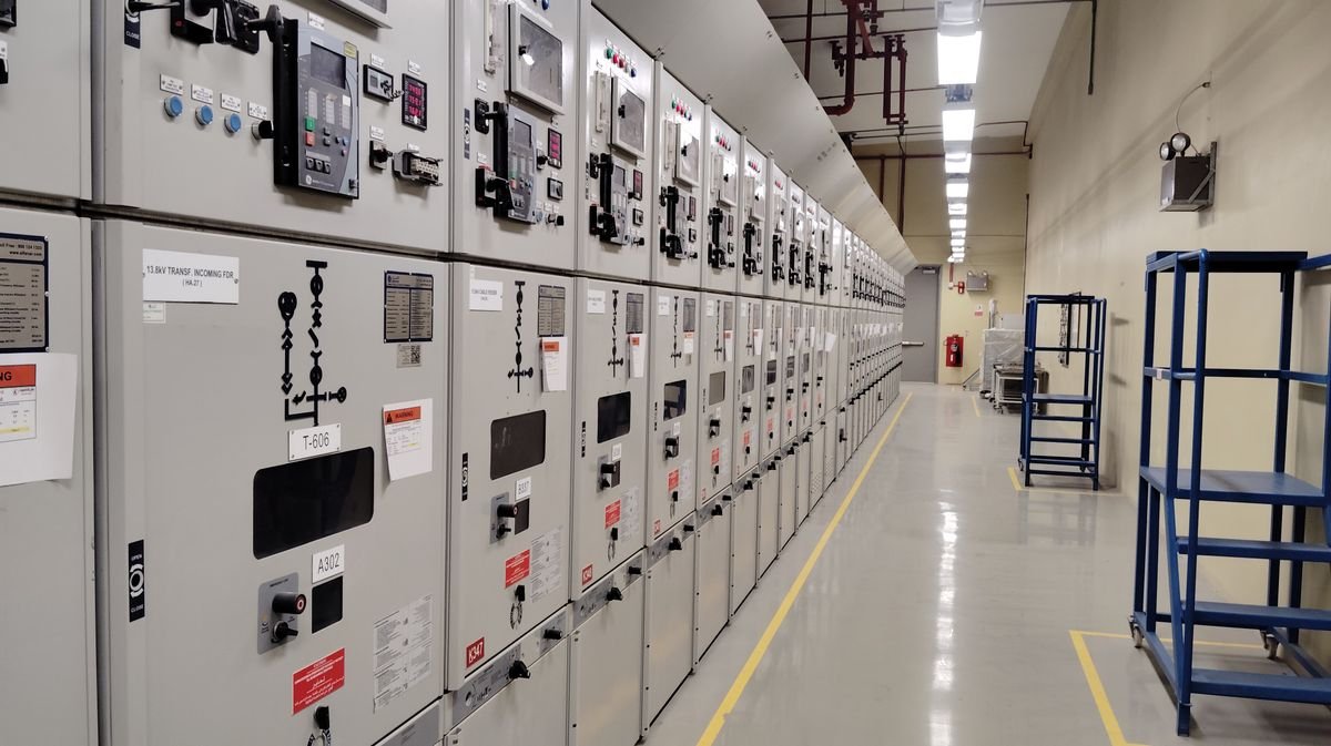 A long row of industrial electrical control panels in a well-lit control room