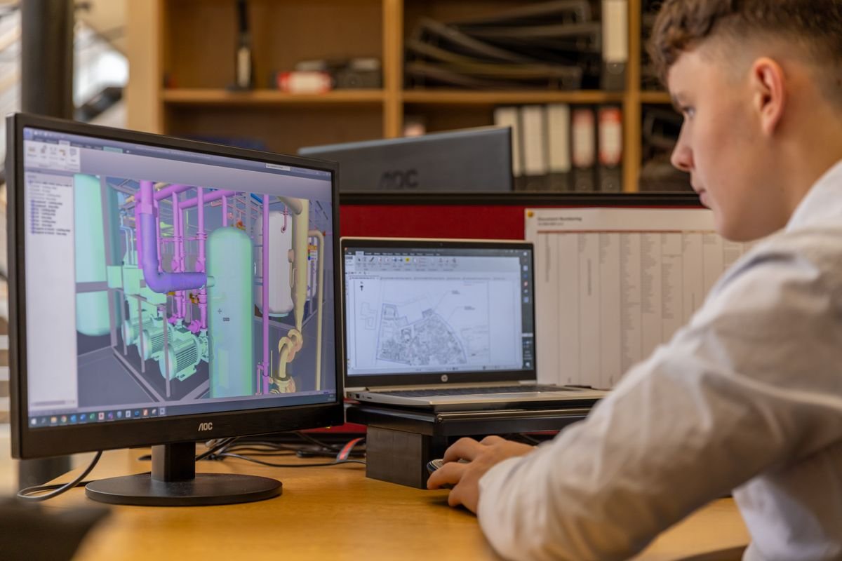 Engineer reviewing a 3D CAD model on dual monitors at an office workstation