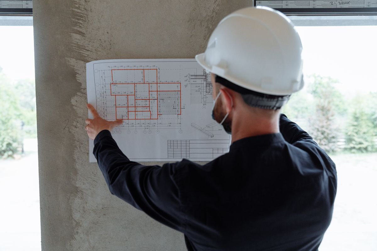 Engineer in a hard hat reviewing a floor plan drawing