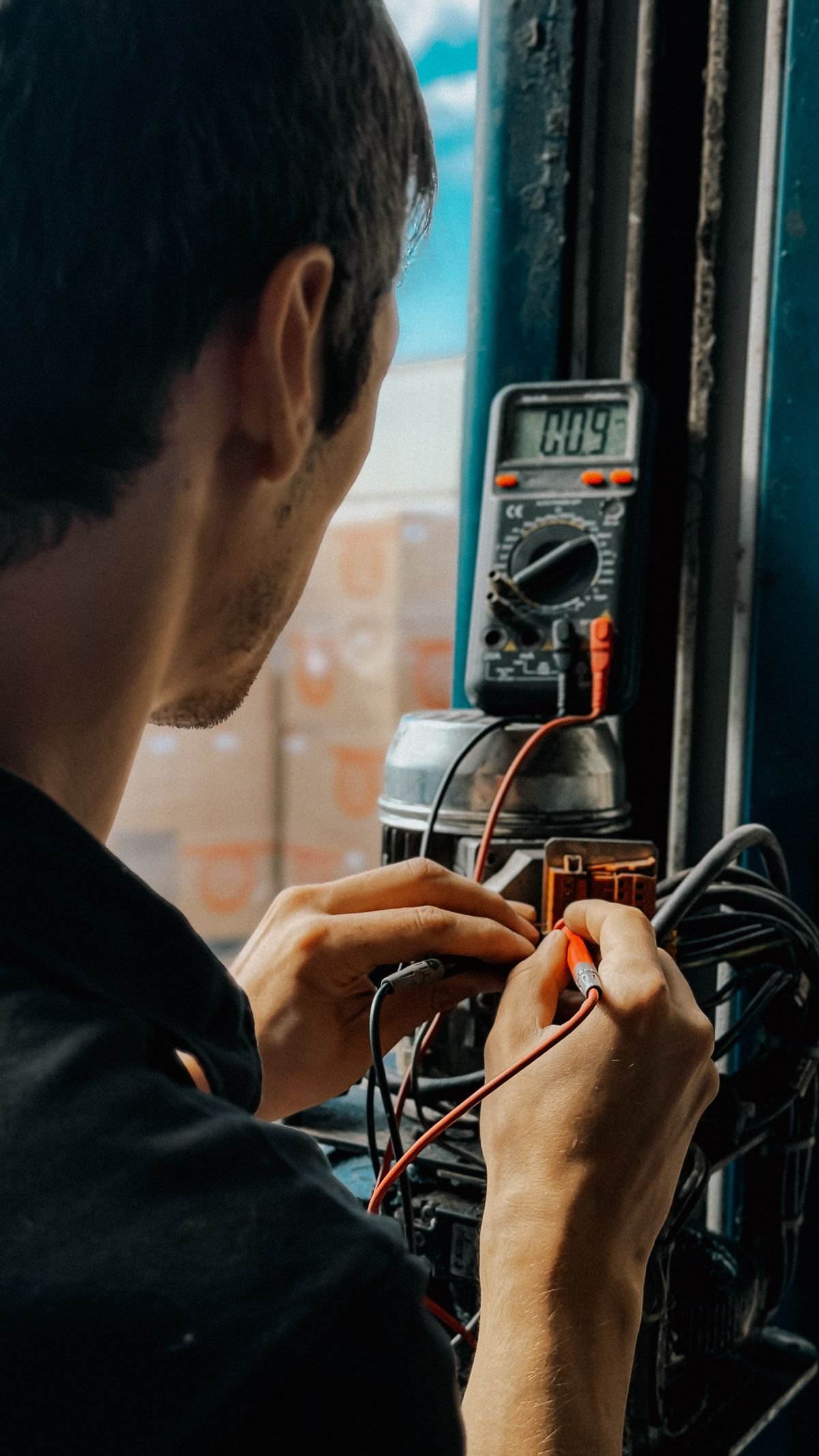 Electrician using a multimeter to check voltages on equipment
