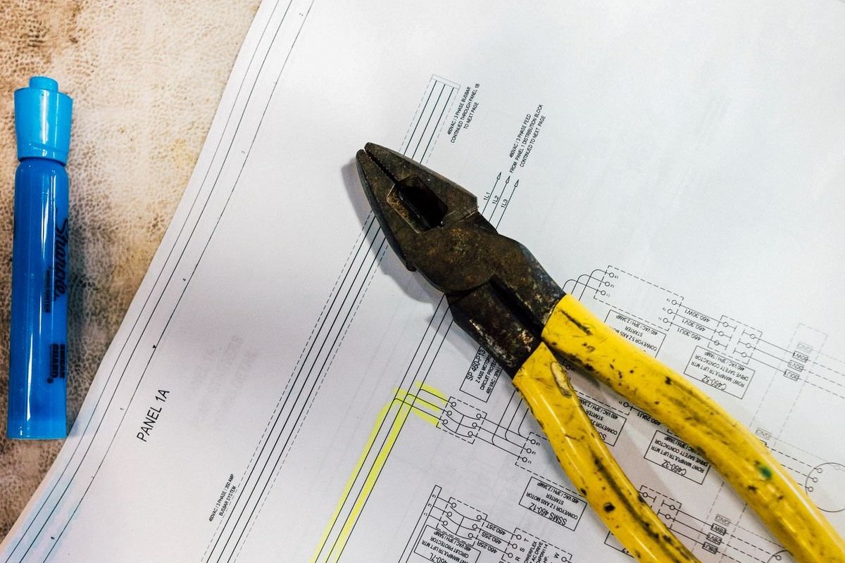 Pliers resting on an electrical schematic drawing on a workshop table