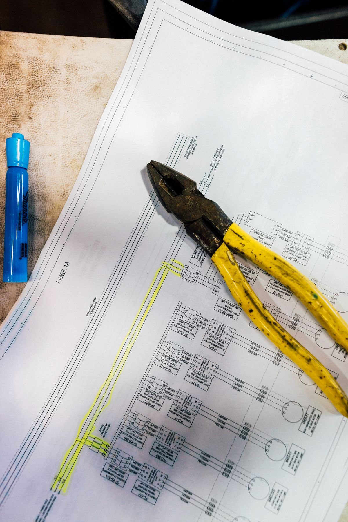 Pliers resting on an electrical schematic drawing on a workshop table