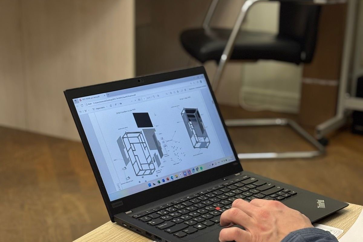 Design engineer reviewing technical blueprints on a laptop at a desk