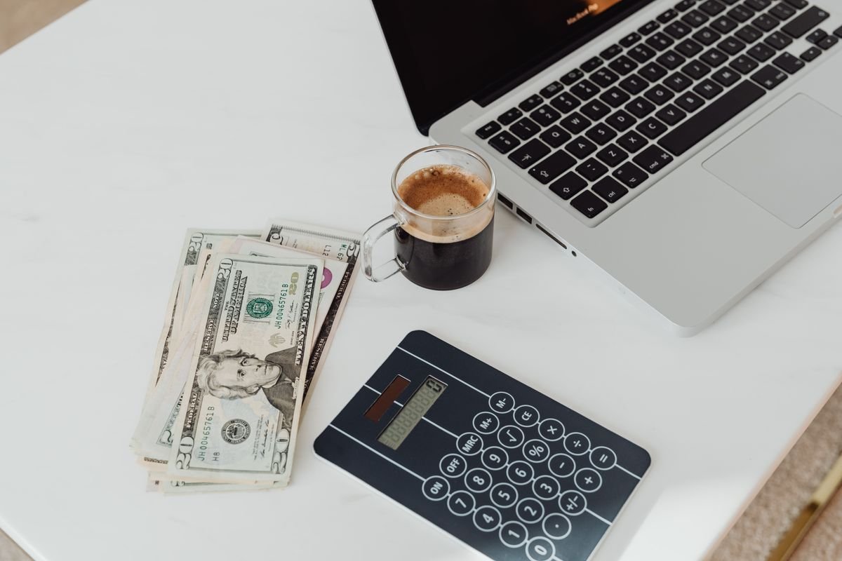 Laptop, calculator, and money on a desk while planning an AI tools budget