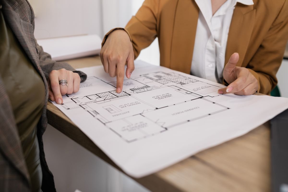 Two engineers leaning over plans and reviewing design details together
