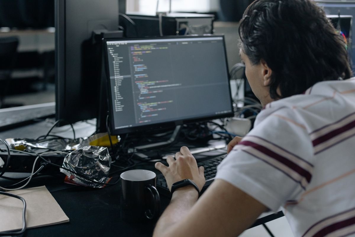 Engineer working at a workstation with a monitor showing code
