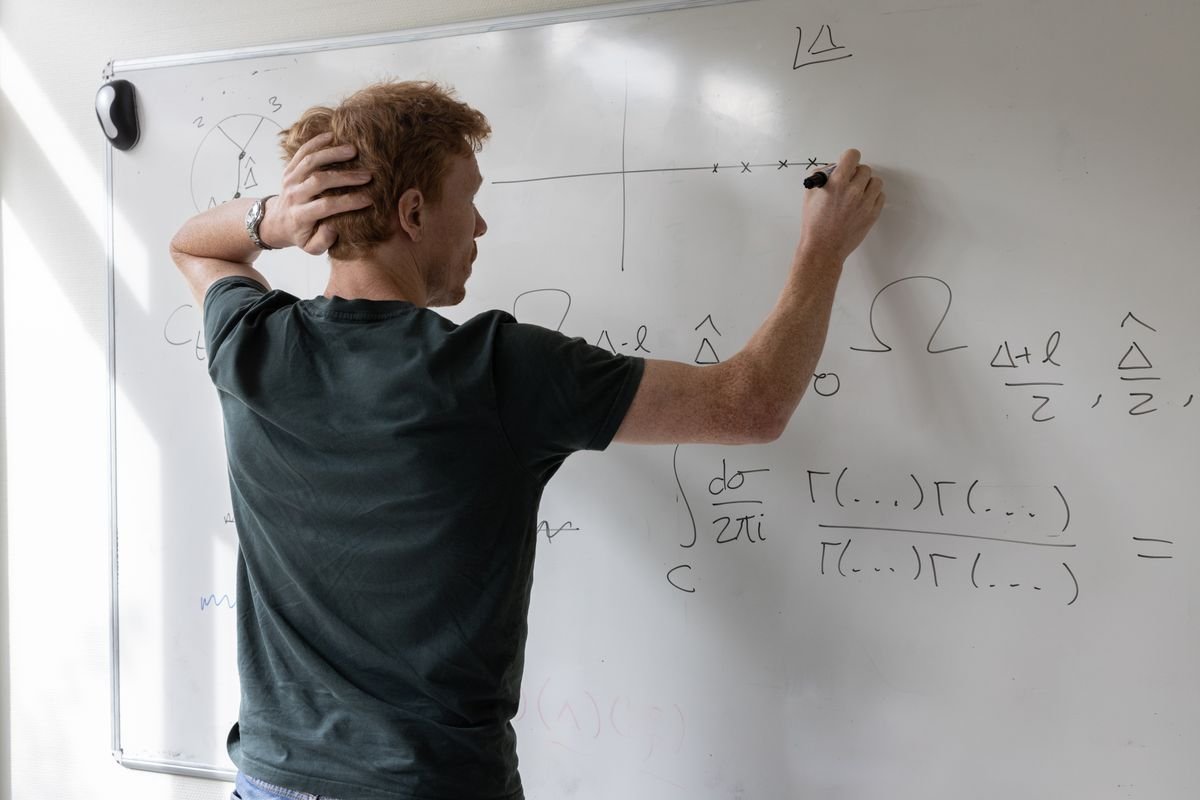 An engineer writing multi-step equations on a whiteboard