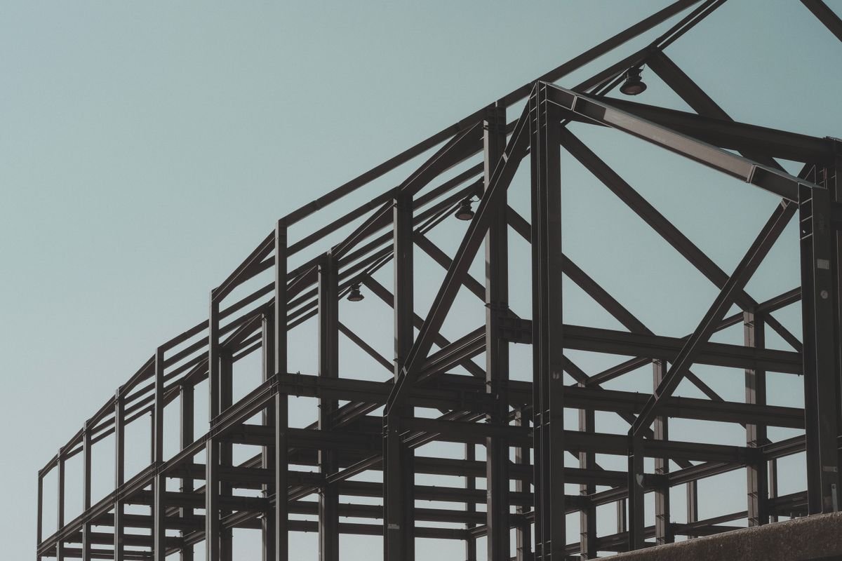 The steel frame of a building under construction against a clear sky