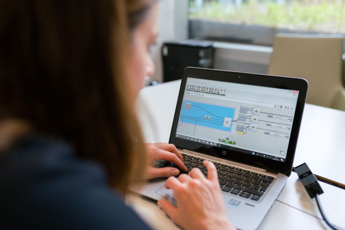 An engineer working at a laptop that shows a parametric, node-based design workspace