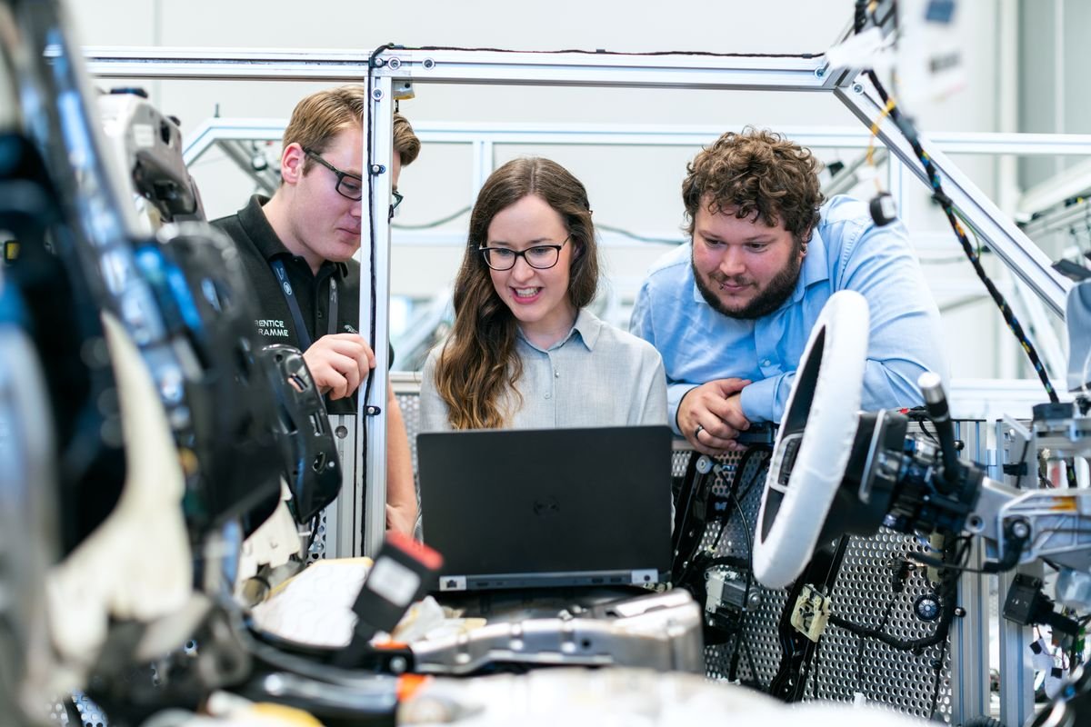 Three engineers reviewing work on a laptop together in an engineering lab