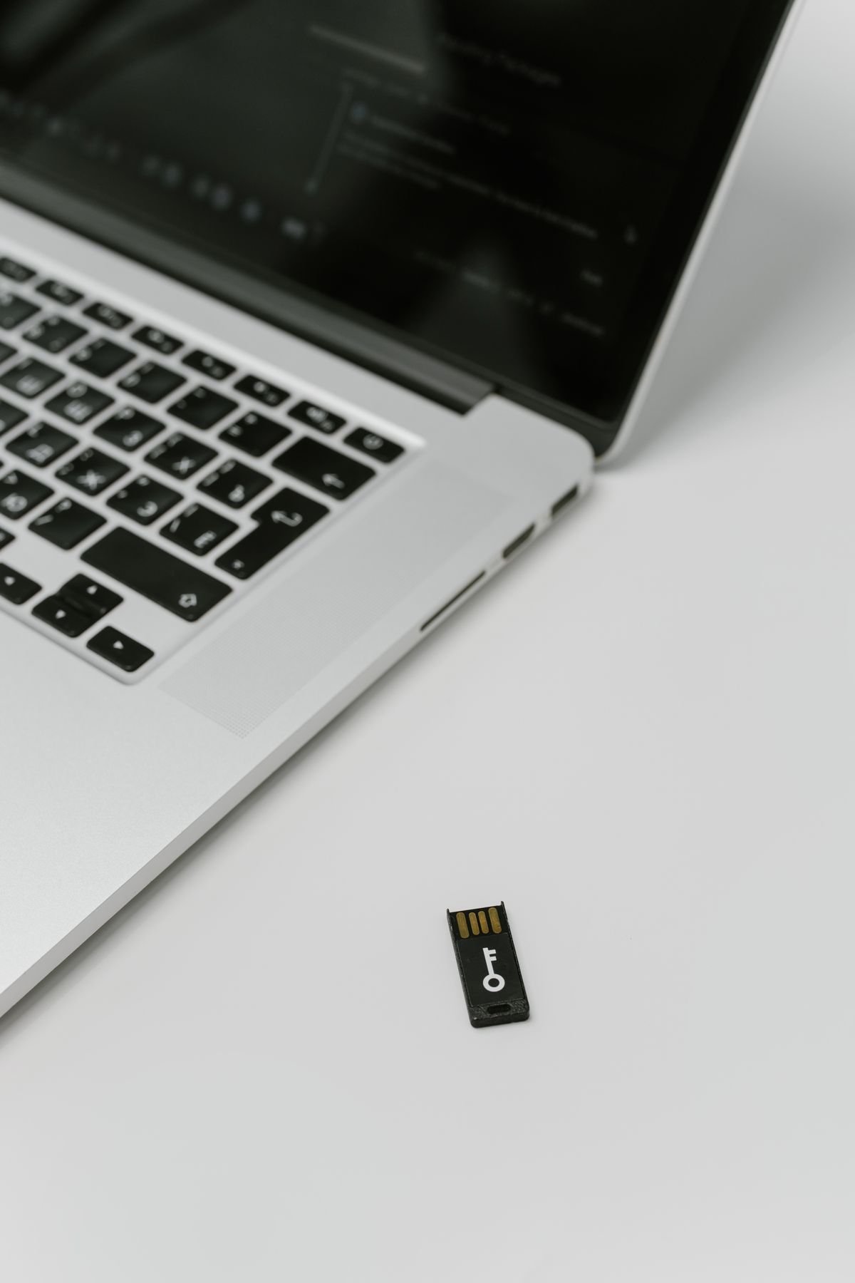 A physical USB security key beside a laptop illustrating data protection and access control
