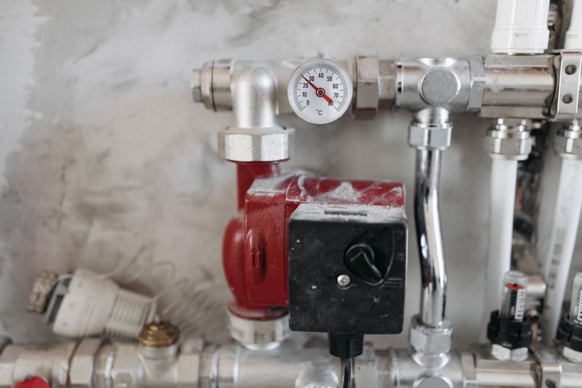 An industrial temperature gauge marked in degrees Celsius on a manifold of steel pipes